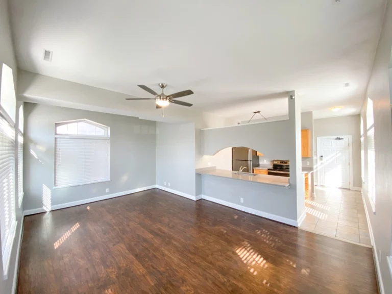 Photograph of a livingroom with wood floors and view into kitchen.