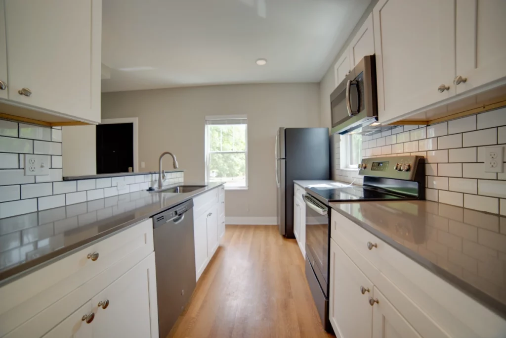 An apartment kitchen with slate grey appliances, white cabinets, and white subway tile backsplash.